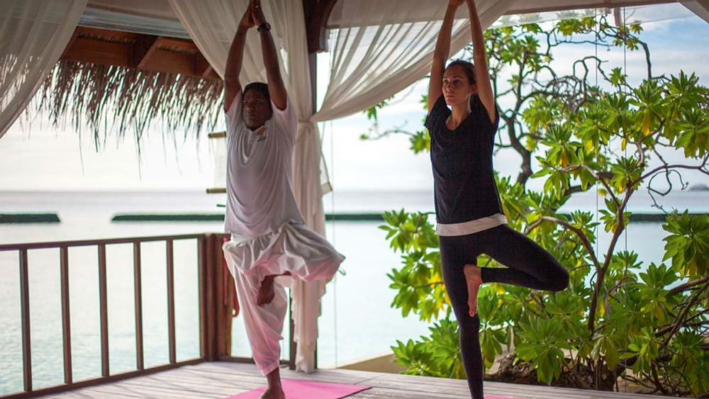 Couple doing yoga in a pavilion at Constance Moofushi