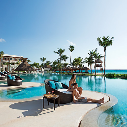 Couple on a sun lounger by the pool at Secrets Akumal