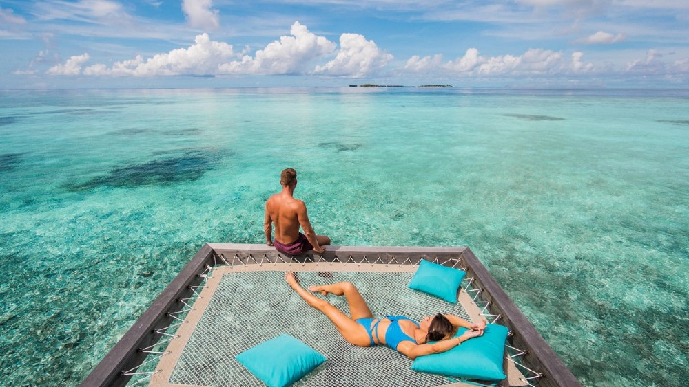 Couple in an overwater villa at Hurawalhi Island Resort