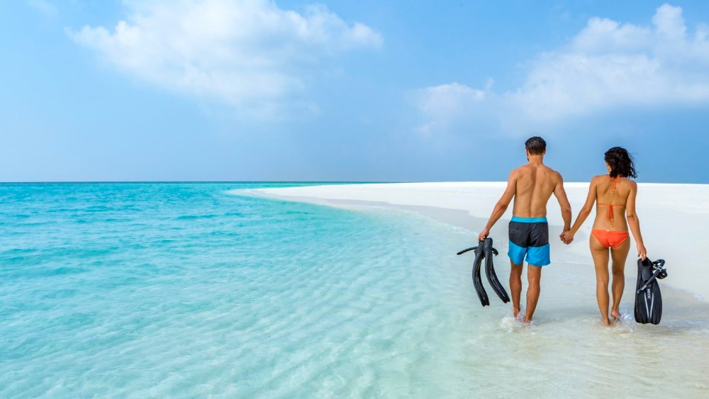 Couple on the beach with snorkelling gear at Hurawalhi Island Resort