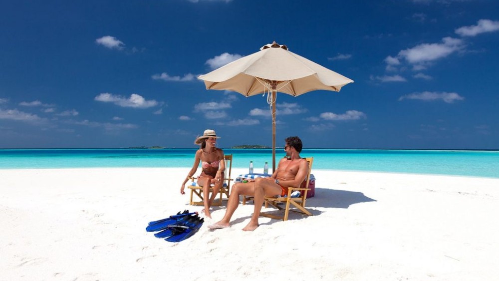 Couple sitting on a private beach at Vilamendhoo Island