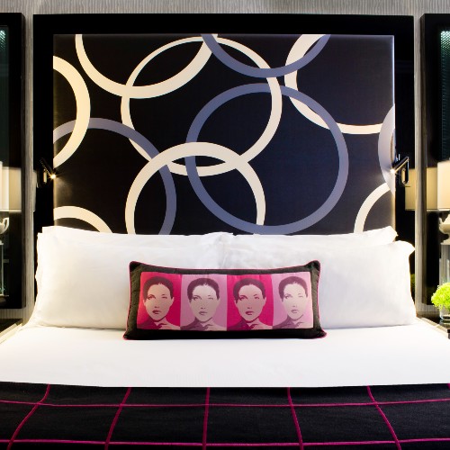 King bed with a pillow with faces on it at Kimpton Muse Hotel